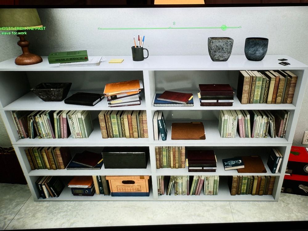 A scene from the RoboCop rogue city video game. It shows a set of white bookshelves with various books and knickknacks on them. Unfortunately, you can’t read the titles of any of the books, but it looks like an impressive collection of classic literature.