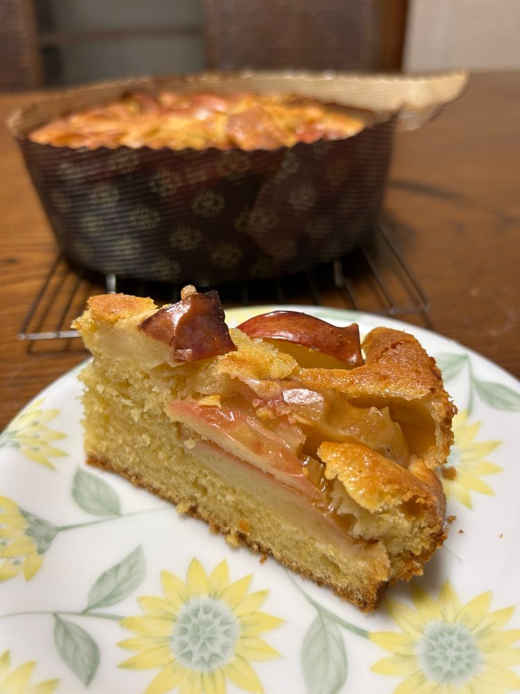 お皿にりんごケーキがひと切れ乗っている写真。生地の上にスライスしたりんごが乗せられて一緒に焼いてあるタイプのケーキ。