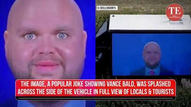 Screenshot of a television news story showing a doctored photo of JD Vance as a bald, wide-eyed, pudgy-faced baby man. Very disturbing. Chyron reads: “The image, a popular joke showing Vance bald, was splashed across the side of the vehicle in full view of locals & tourists” I believe this is from his Scotland trip. 
