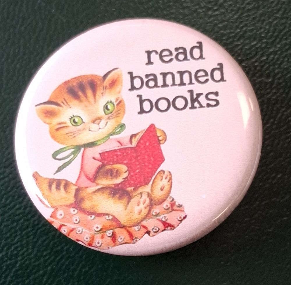 Decorative button shows a sweetly smiling orange kitten reading a red book while seated on a pink ruffled pillow. The kitten has a green ribbon tied around its neck. The text says "Read Banned Books".