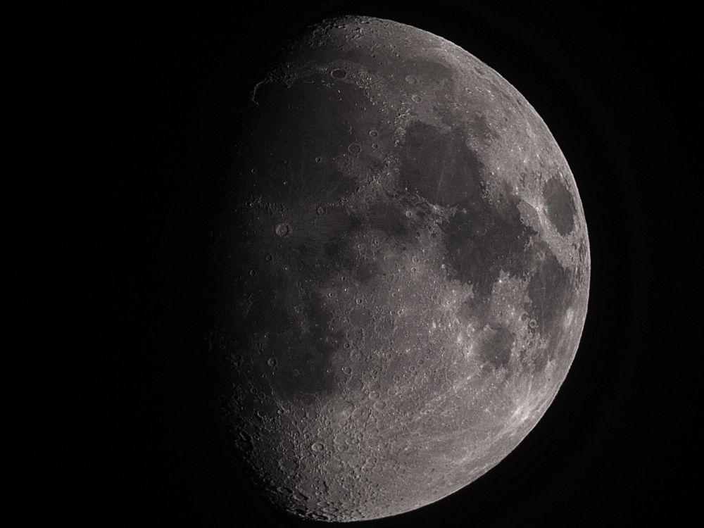 A telescopic image of the Moon in the waxing gibbous phase showing many impact craters and smooth, dark plains. 