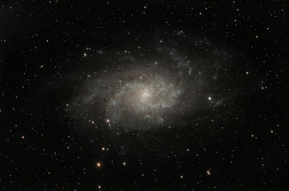 A telescopic image of a spiral galaxy. It somewhat shaped like a pinwheel. 