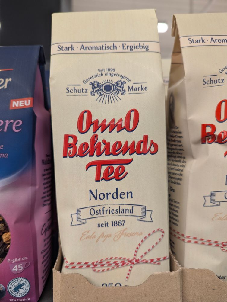 A bag of tea leaves on a store shelf called "OnnO Behrends Tee" in a Sütterlin-inspired cursive that makes it look like "OwO"