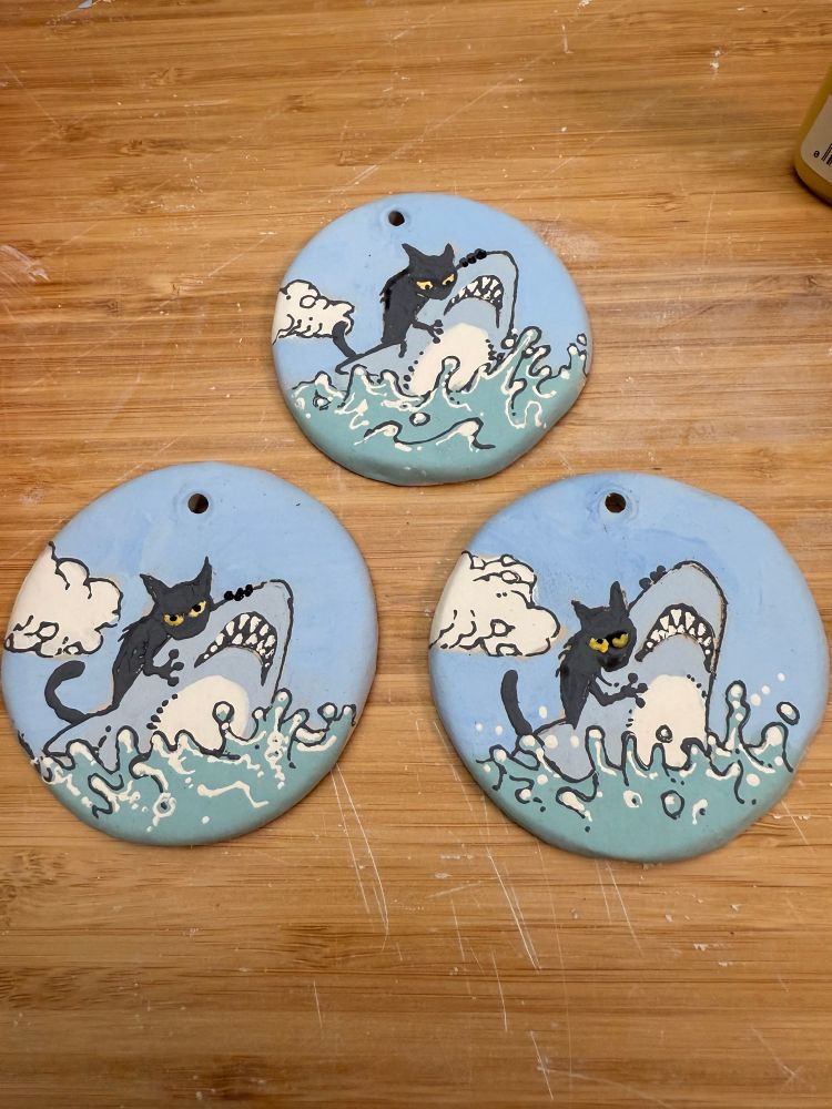 A trio of ornaments featuring a black cat biting a shark. Not my idea, but I tried to make it my own.

#Ceramics #ClayArt #Pottery #Clay #ArtTherapy #AutisticArtist #ADHD #Sculpture #Art #Artist