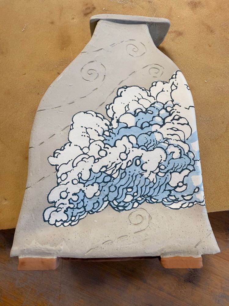 A bone dry clay vase lays on a table. It has stylized clouds painted on it. Wind trails are etched into the unpainted areas of the clay.

#Ceramics #ClayArt #Pottery #Clay #ArtTherapy #AutisticArtist #ADHD #Sculpture #Art #Artist #Vase #Clouds