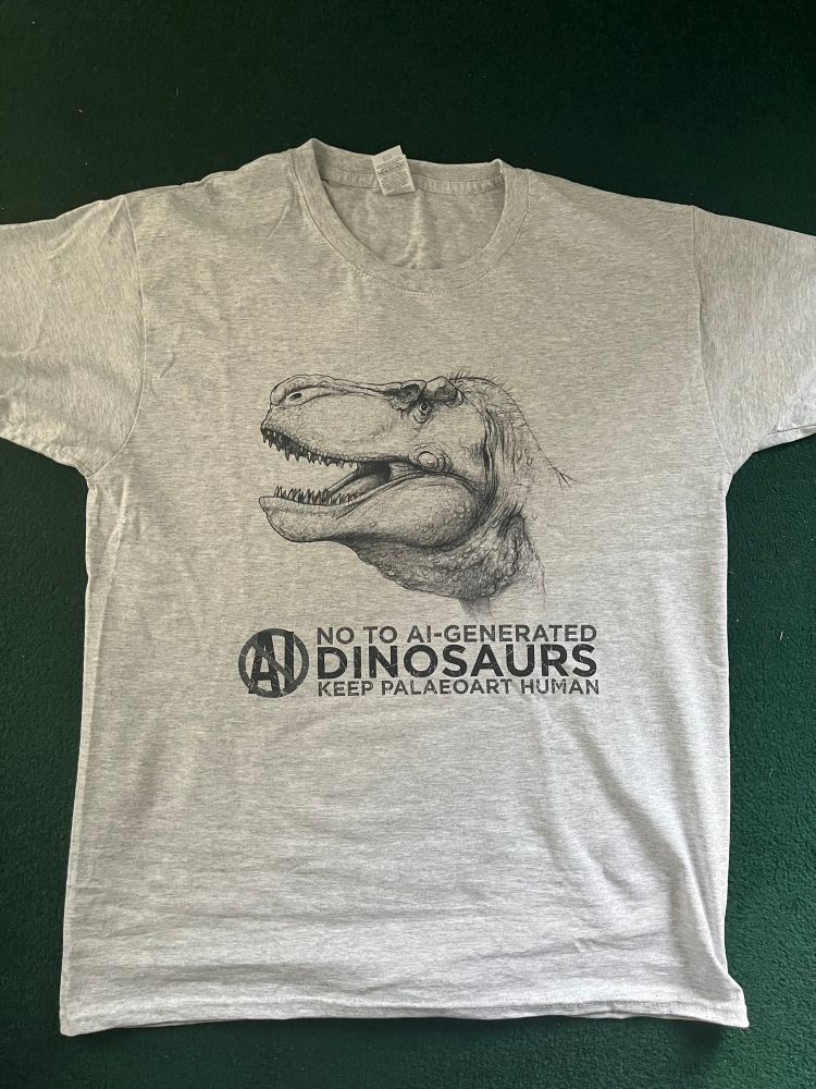 A grey T-shirt, with a simple black print on the front. 
The print includes one of my pencil sketches of a T. rex, and beneath it a “No AI” logo, along with the words “No to AI-Generated Dinosaurs. Keep Palaeoart Human”