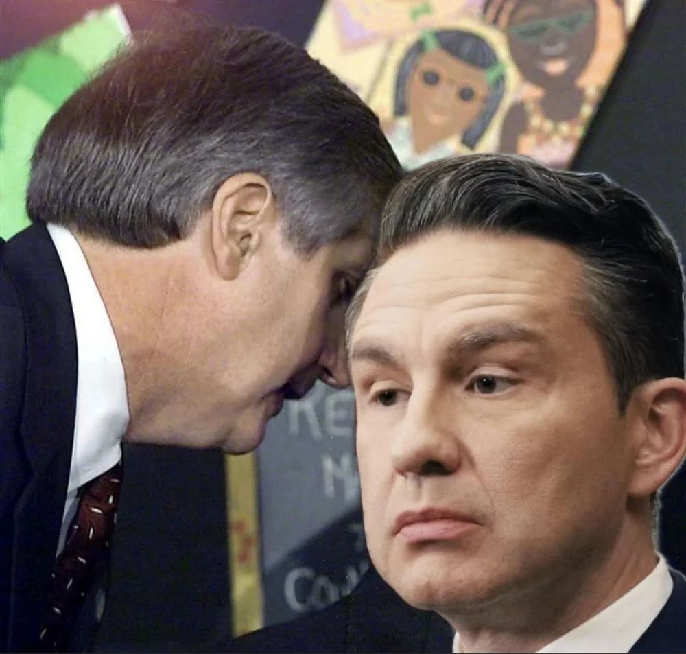 A man appears to speak quietly into Pierre Poilievre's ear."