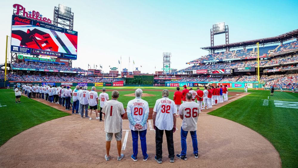 Chris Roberts and Richard Ashburn Jr. stand alongside Mike Schmidt and Steve Carlton during the National Anthem.