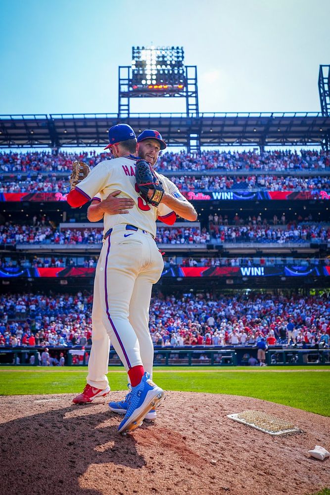 Bryce Harper and Zack Wheeler hug on the mound. They are wearing the cream Phillies uniform