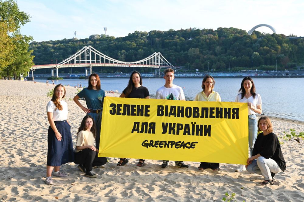 Staff of the new Greenpeace Ukraine office hold a banner reading 'зелене відновлення для україни' ('Green reconstruction for Ukraine') by the bridge to Trukhaniv Island in central Kyiv