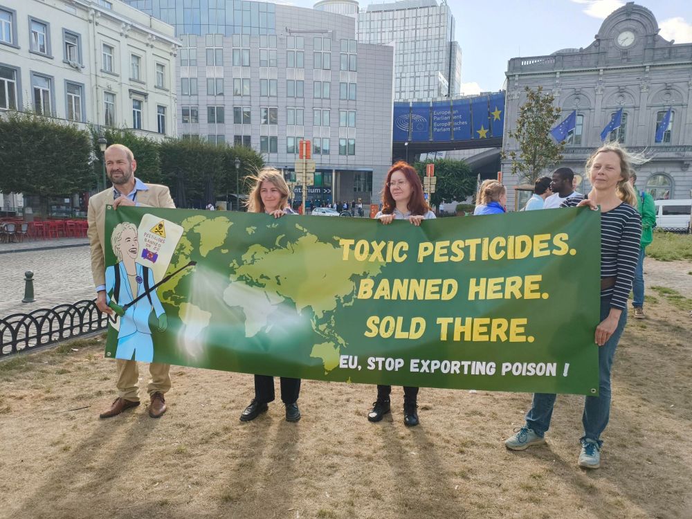four people holding a green banner with a world map and text reading TOXIC PESTICIDES BANNED HERE. SOLD THERE. 
EU, STOP EXPORTING POISON!

they're standing in front of the European Parliament in Brussels