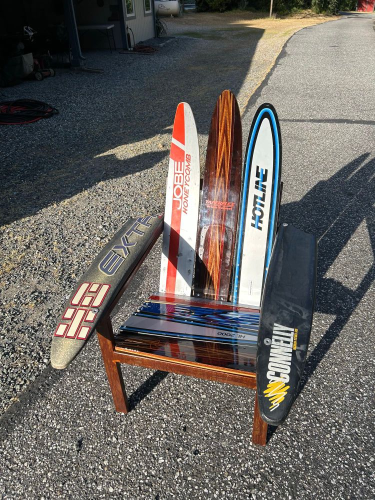A chair made of welded metal that has been painted and old skis for the seat, arms and back of the chair. 