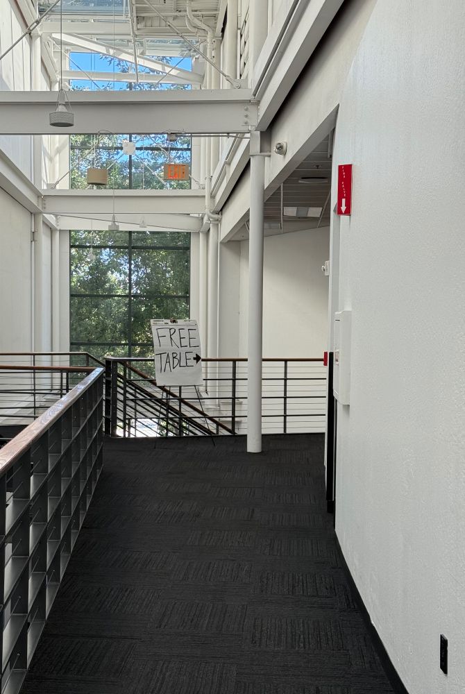 long empty hallway with sign at end pointing out where the free table is
