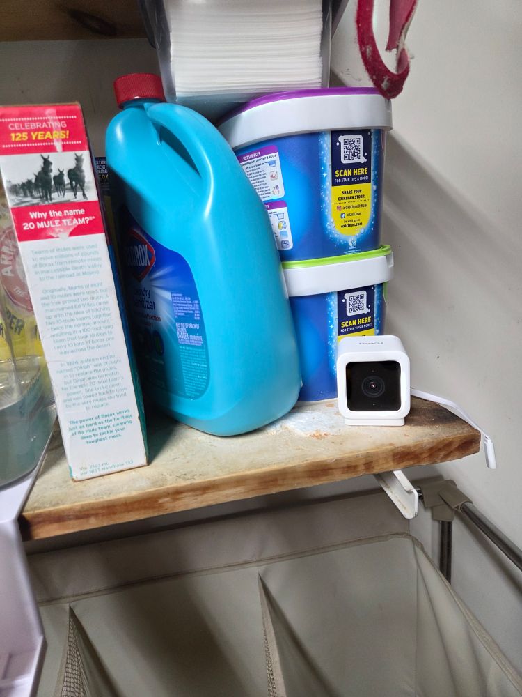 Mini camera on a shelf with laundry detergent 