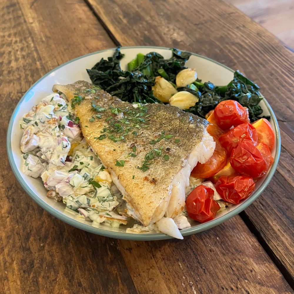Pan-seared cod with smashed new potato salad, steamed greens and oven-baked tomatoes