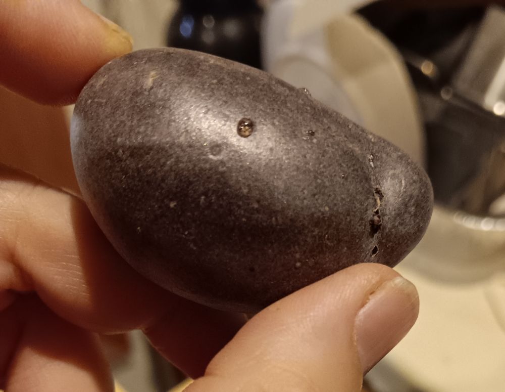 A small purple potato. There is a tiny drop of liquid on the surface