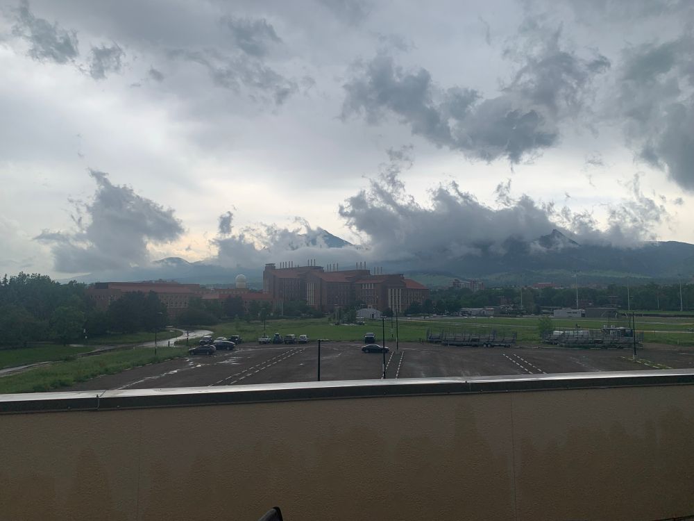 The flatirons in Boulder, covered by clouds and with the biotech building in the foreground 
