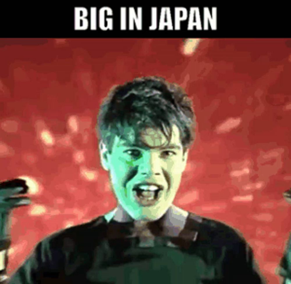 a young man with green paint on his face is standing in front of a red background with the words big in japan written on it