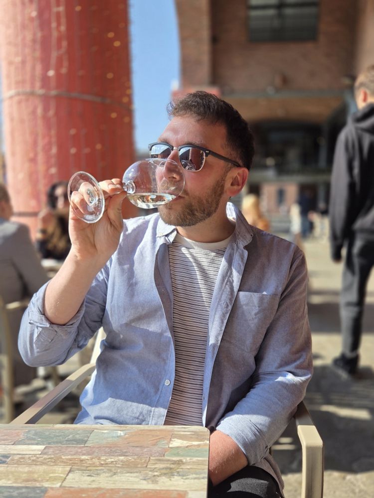 Man in sunglasses drinks a glass of wine in the sunshine at the Albert Dock in Liverpool 