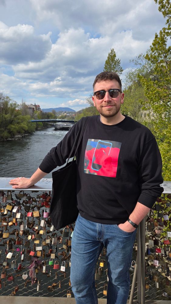 Man in sunglasses looks at the camera on a bridge overlooking a mirror