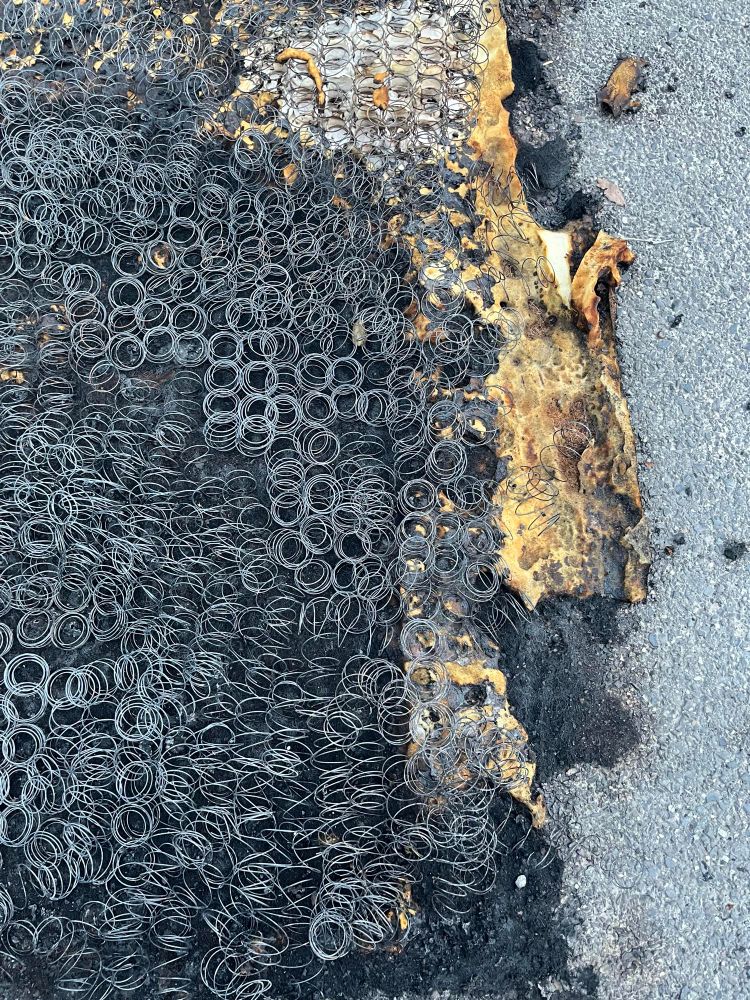 Remains of a burnt mattress on pavement