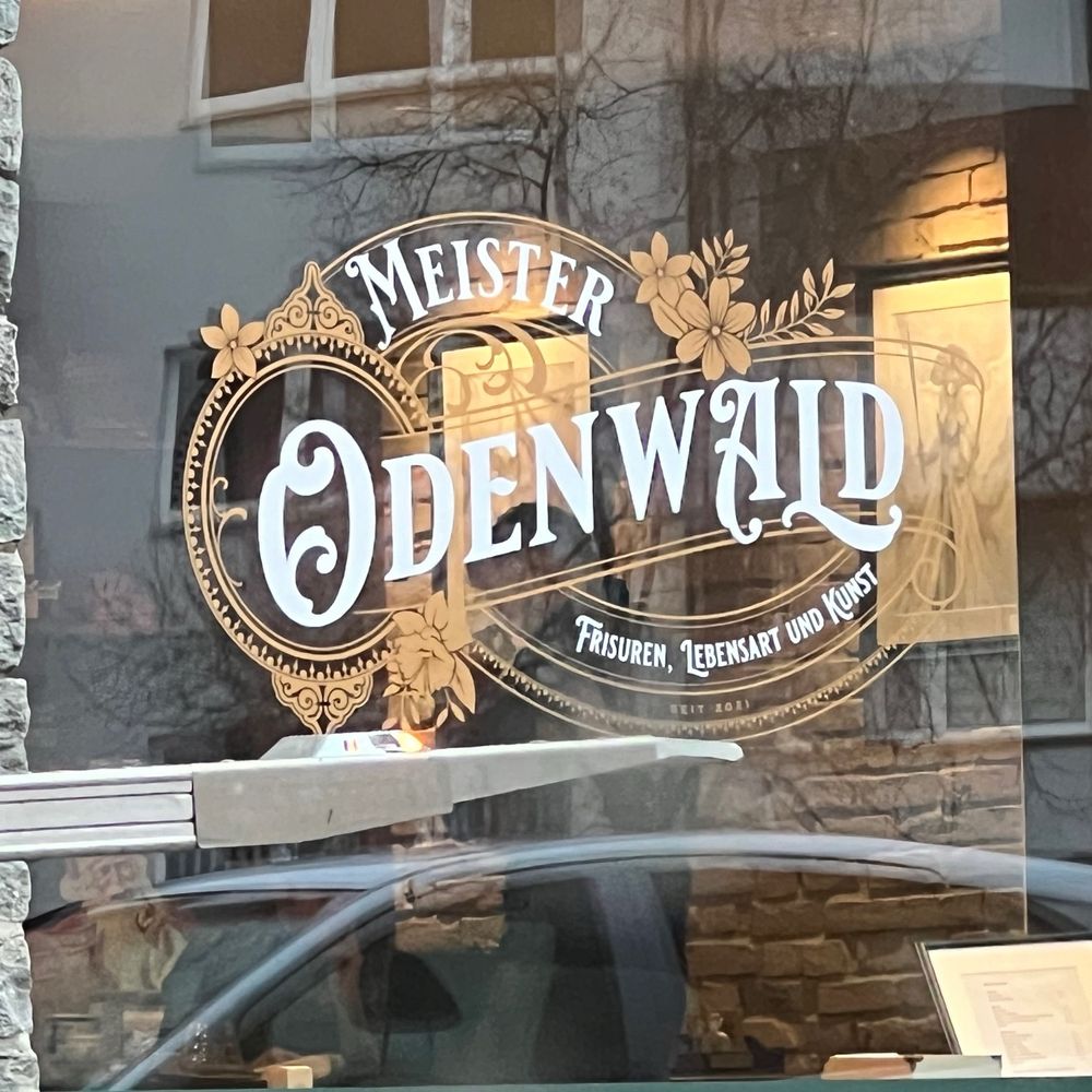 Ein Bild von einem Schaufenster mit dem 
Firmenname Meister Odenwald. Dazu der Untertitel Frisuren, Lebensart und Kunst.