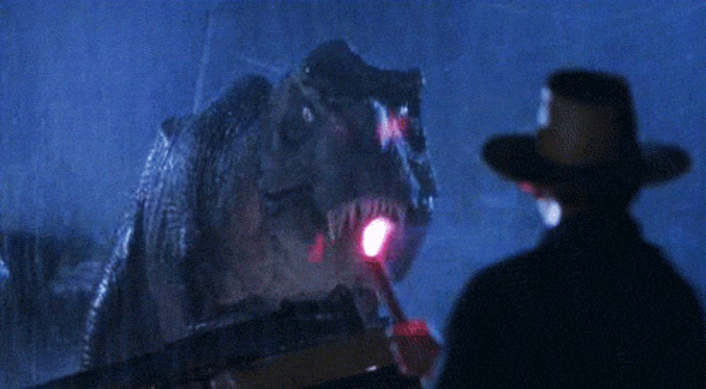 a man in a cowboy hat is standing in front of a dinosaur with a red light in its mouth