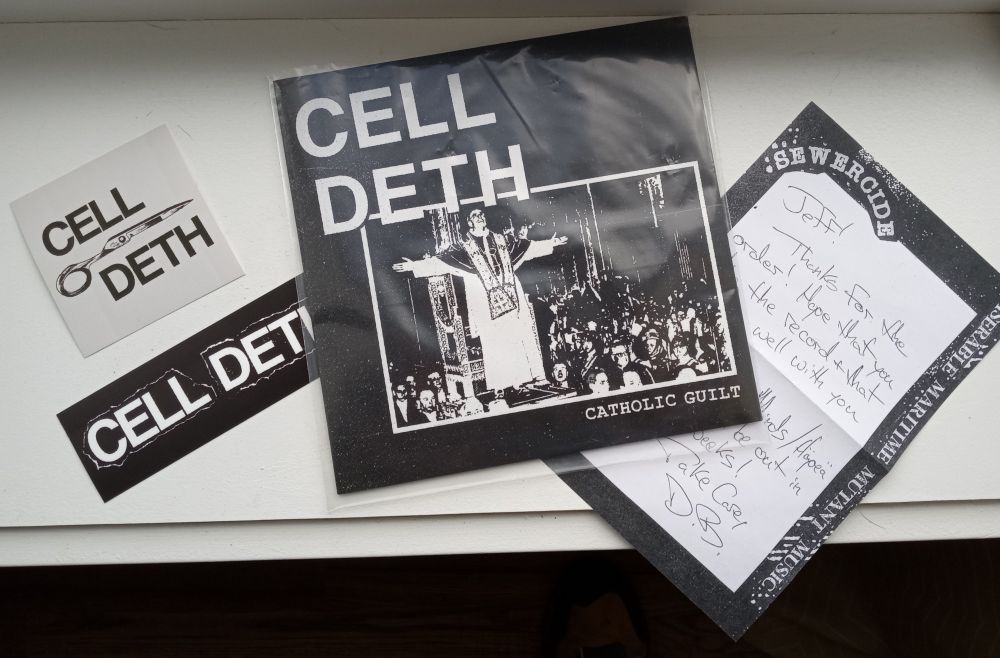 Image of Cell Deth's debut seven inch record "Catholic Guilt" surrounded by two Cell Deth stickers and a short note on Sewercide Records official stationary. The edge of the note reads "Miserable Maritime Mutant Music."