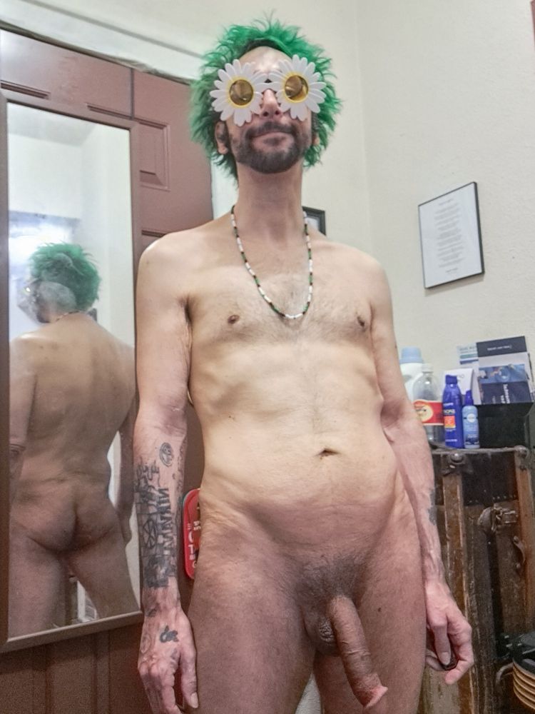 Me entirely naked, with bright green spikey shaggy hair reminiscent of grass.  I am wearing white flower sunglasses with yellow lenses.  I am standing in front of a mirror showing my cute butt and shapely back. I am stoned and my penis is semi engorged, hanging low like a wide long elephant trunk. I'm wearing a replica Jim Morrison necklace.