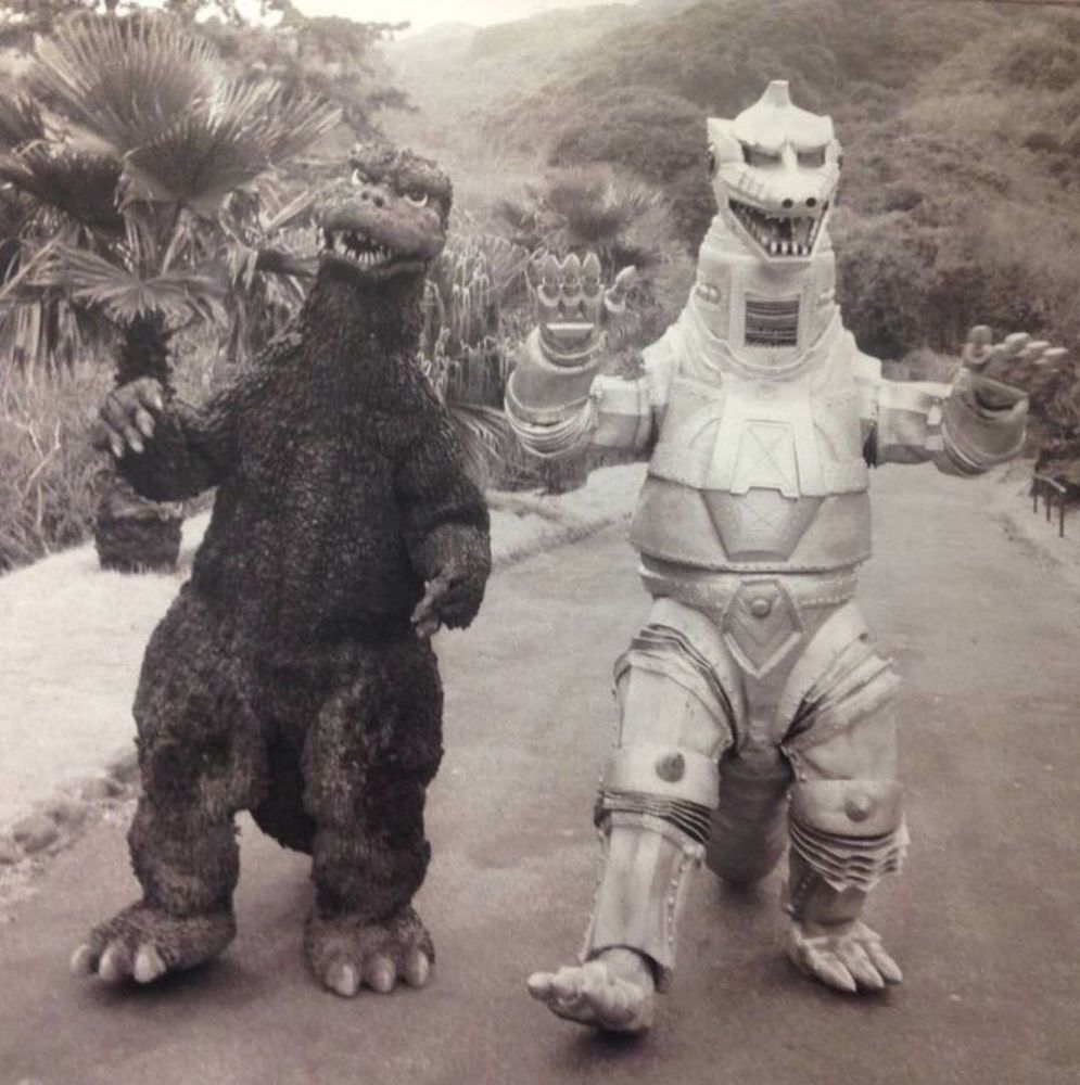 Godzilla and Mechagodzilla dancing down a road together