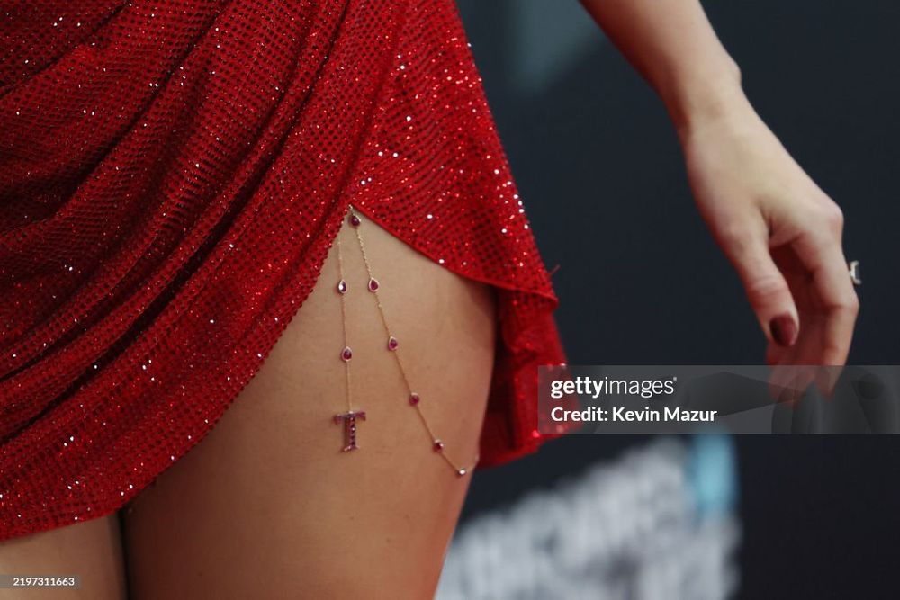 an upclose of the T chain on taylor swift's thigh under her red dress by kevin mazur for gettyimages.