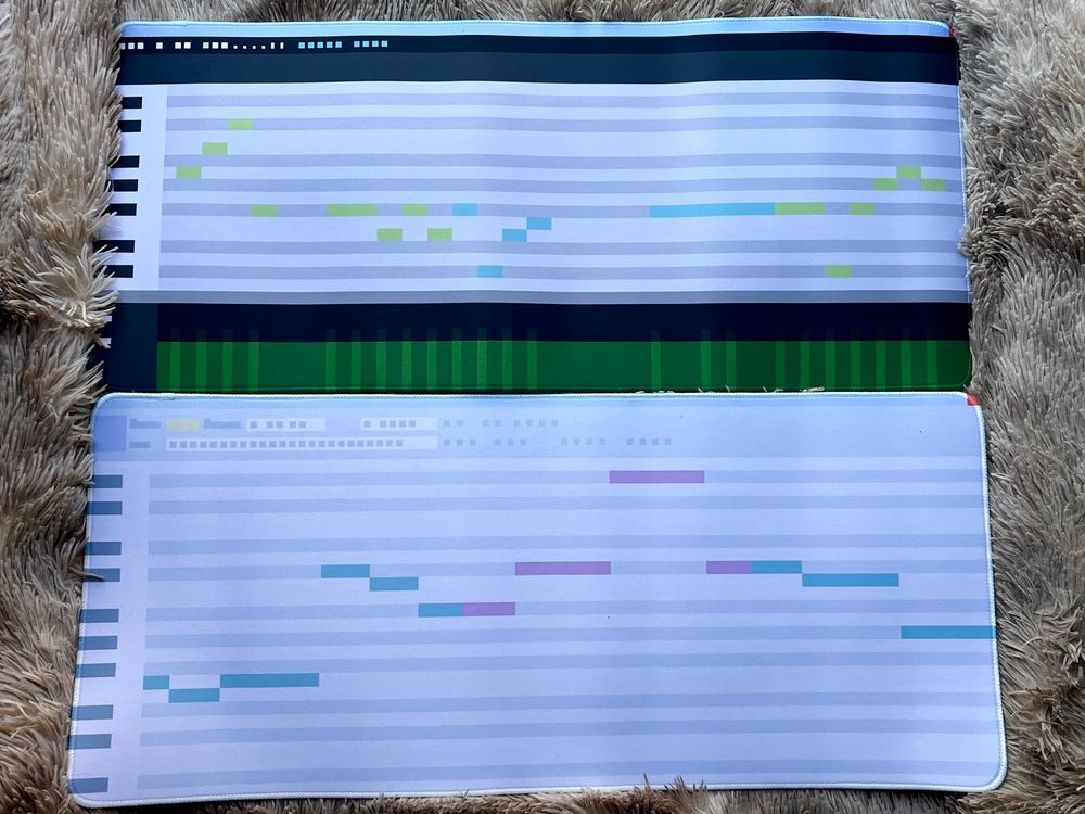 Two desk mats, one featuring the UI design of Vocaloid 4 and the song “Unknown Mother Goose” by Wowaka, and the second featuring the UI design of UTAU and the song “Heat Abnormal” by iyowa