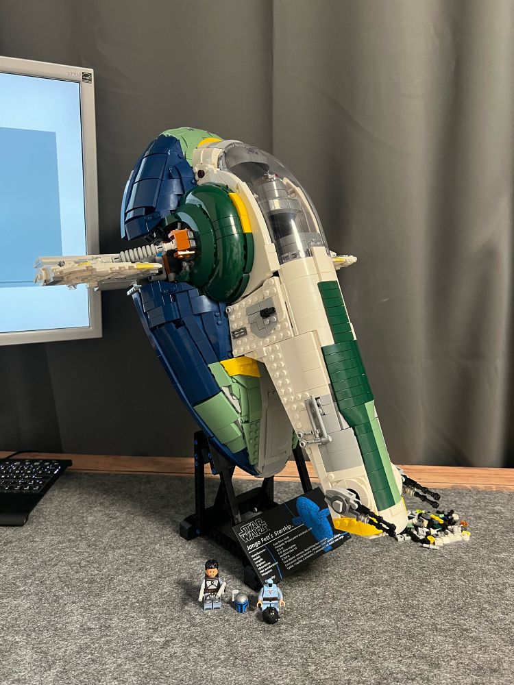 Lego Star Wars Jango Fett‘s spaceship 75409 on the stand front right view. Two minifigures standing in front of it, Jango Fett and young Boba Fett, who is missing his head piece
