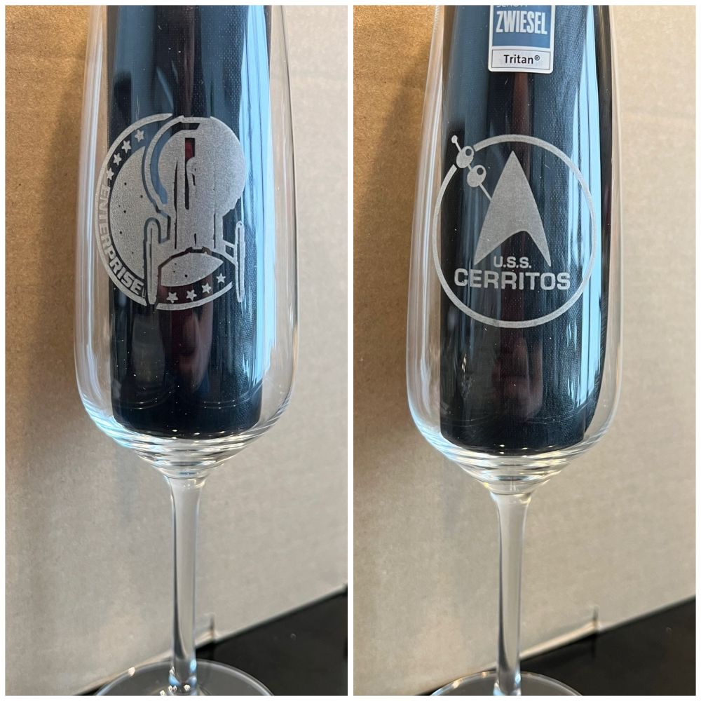 Two champagne glasses with laser engraved logos. On the left the „Enterprise Logo“ from the NX-01 / Star Trek Enterprise and on the right the Logo of the bar of the USS Cerritos from Star Trek Lower Decks