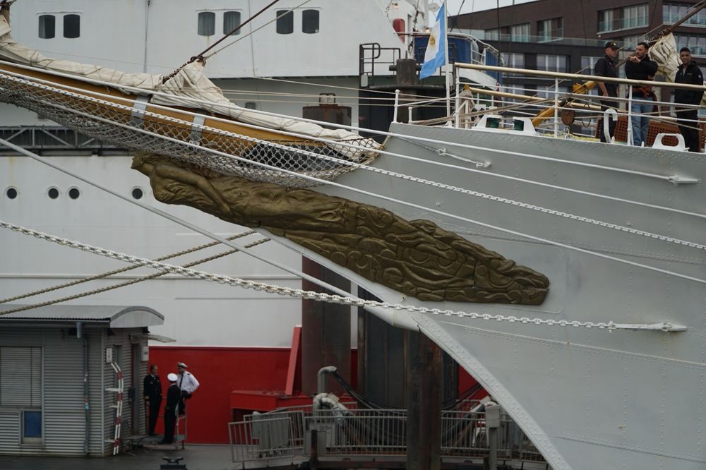 The figurehead of the A.R.A. Libertad the golden body stretches from the white ships hull to yellow bowsprit. In top of which the Jibs are neatly packed
