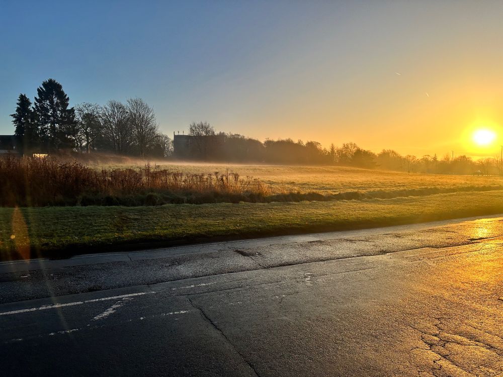 Landscape of rising sun on icy grassland in yorkshire