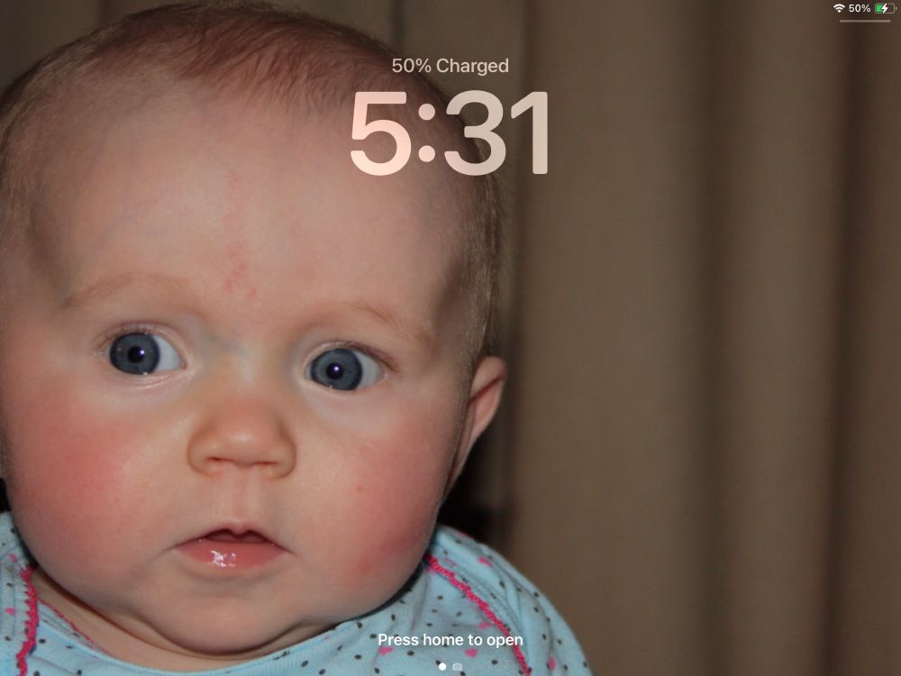 Close-up of an adorable blue-eyed baby girl wearing a blue onesie with pink trim.