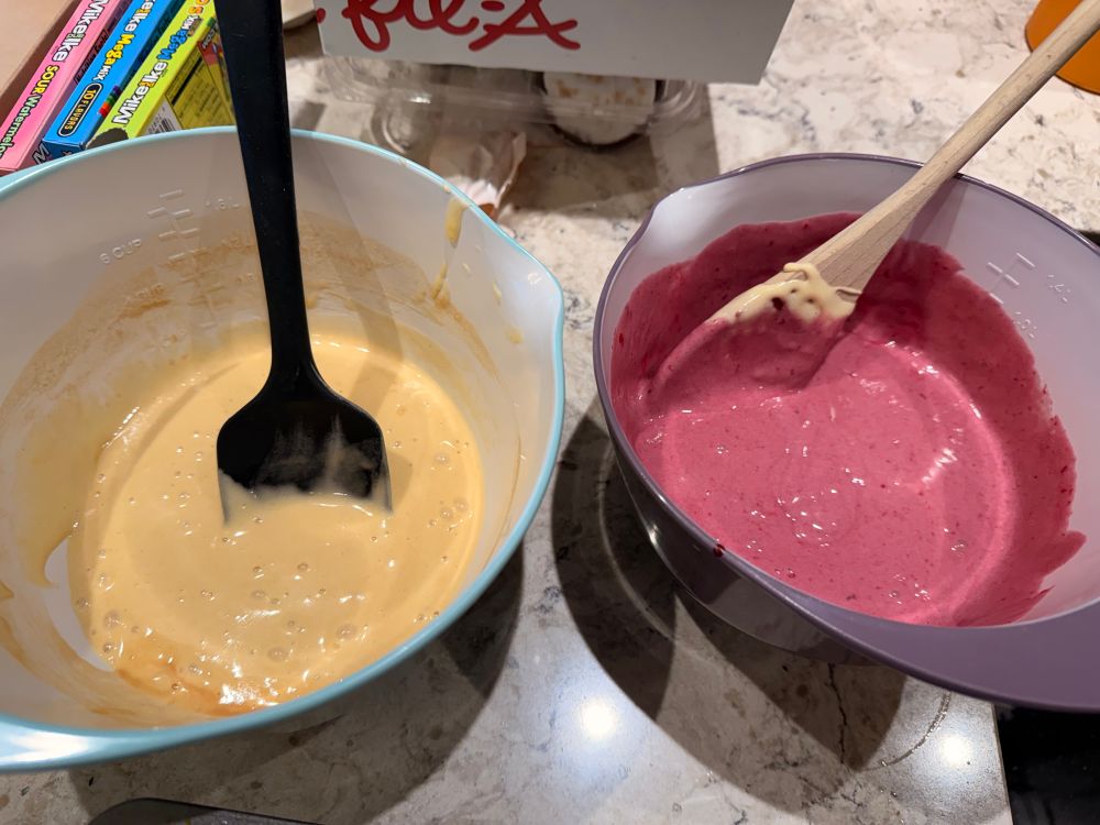 Two bowls of cake batter, one yellow the other purple.