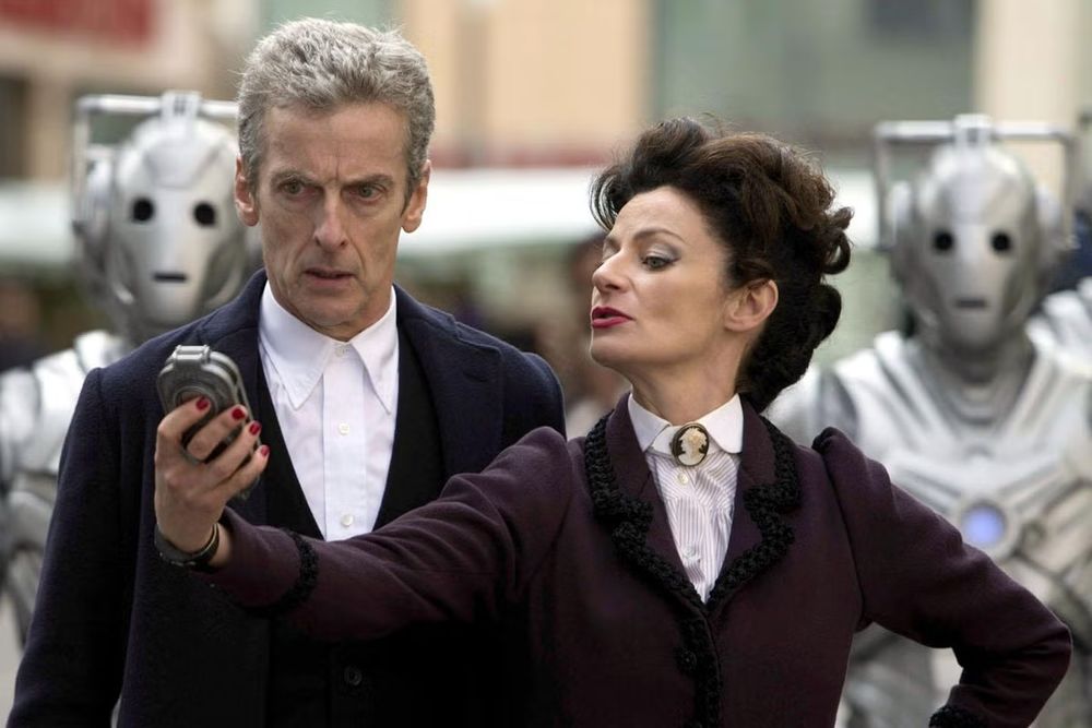 Michelle Gomez as Missy in Doctor Who, with the Doctor and Cybermen in the background