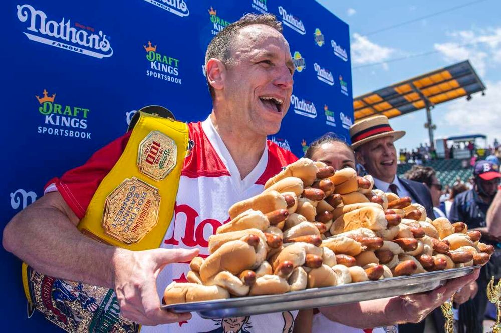 Joey Chestnut holds a plate of 71 hot dogs after winning his 17th mustard belt, king shit