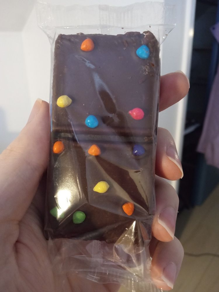 Me holding a Cosmic Brownie in its wrapper. It's a brownie with little colorful candies on it.
