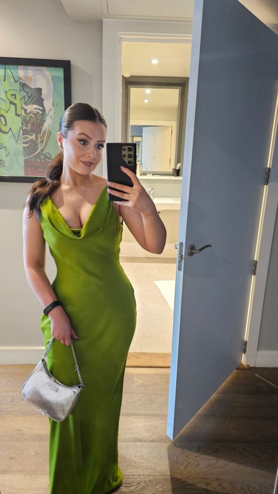 Me taking a selfie in a grass green dress with a silver bag. My hair is tied up in a ponytail.