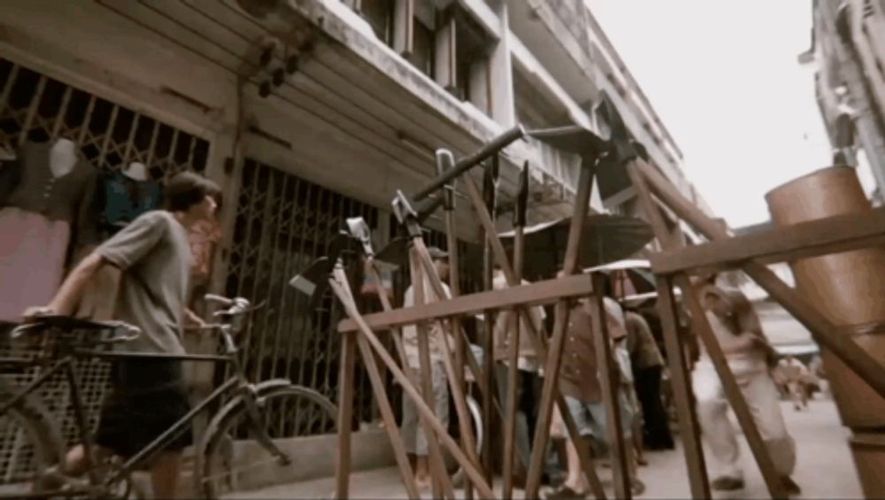 a man riding a bike on a street with a wooden fence