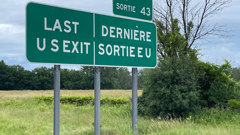 Bilingual traffic sign in English and French informing about the last exit in the US near a border crossing to Canada. 