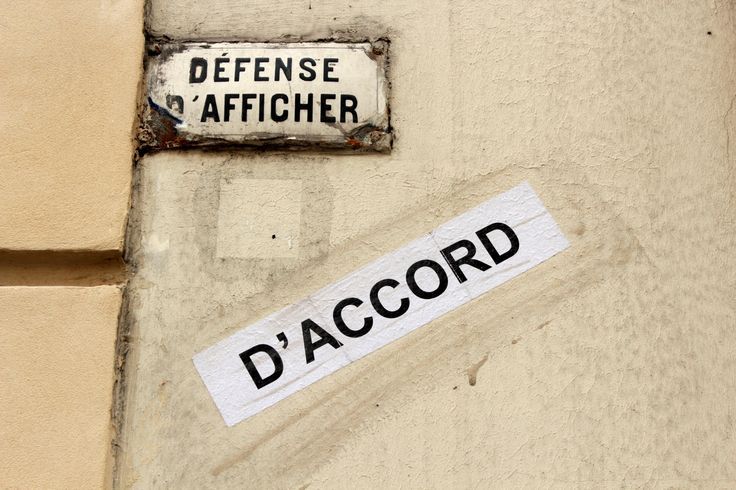 Panneau "Défense d'afficher" sous lequel quelqu'un a coller une affiche "D'accord"