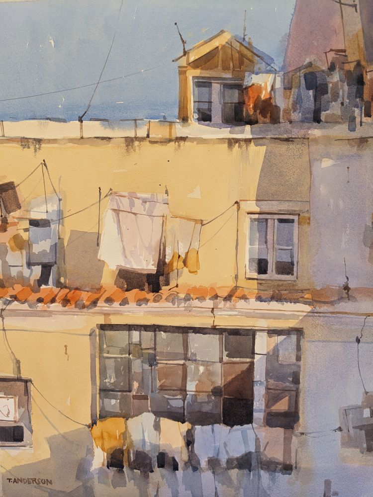 Watercolor painting of laundry hanging out to dry along multiple floors of an apartment building in Lisbon, Portugal. A mutiple-story, pastel yellow apartment building has a stark blue-purple shadow cast upon the right side from another apartment building behind the viewer. On the first floor is a wide, multi-paned screened in window, with various articles of clothing strung to dry in front. The level above has sheets and towels hung on wire and metal structures, with a single window. On the roof is a small entry with more clothes hung to dry, covered in shadow.