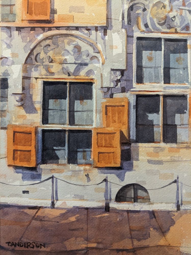 Watercolor painting of the facade of an old government building in Delft, Netherlands. A grey, stone brick building facade covers the upper two-thirds of the scene, with tall, slender windows. The ground floor windows are accompanied by red, wooden shudders. Above the windows are ached reliefs. The sharp sunlight from the left casts dark shadows along the facade and shudders. There is a small half-arched window on ground level along the sidewalk, behind posts strung with a chain. In the foreground is a brick road dappled in purple shadows.
