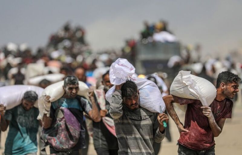 epaselect epa12290446 Internally displaced Palestinians carry bags of flour near a food distribution point in Zikim, northern Gaza Strip, 08 August 2025. Humanitarian organizations have warned of an imminent food catastrophe for thousands of children, a crisis caused by severe food insecurity, a decline in health services, and ongoing restrictions on humanitarian aid and essential supplies. EPA/MOHAMMED SABER