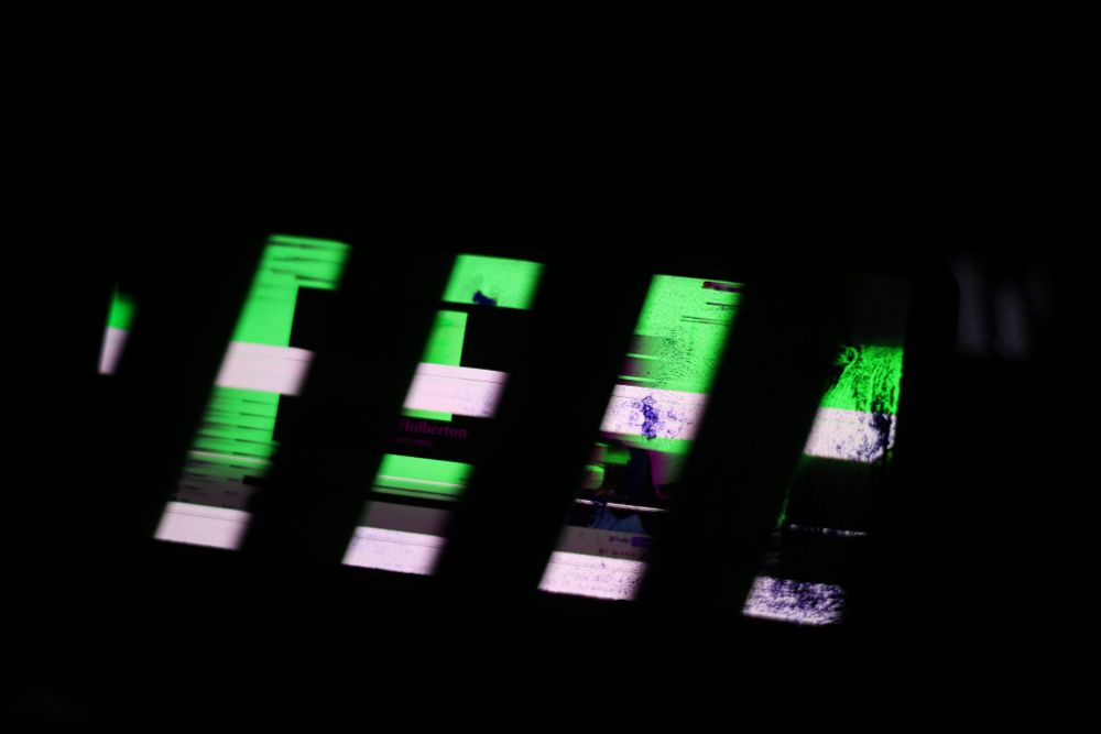 shattered LCD screen - none of what is on the screen is visible, many dead pixels on the bottom of the screen (image right) and the display is full of very large cyan/green visual artifacts, and two white stripes across the entire screen. Shutter speed of the image means the screen has black strobe lines running along it.