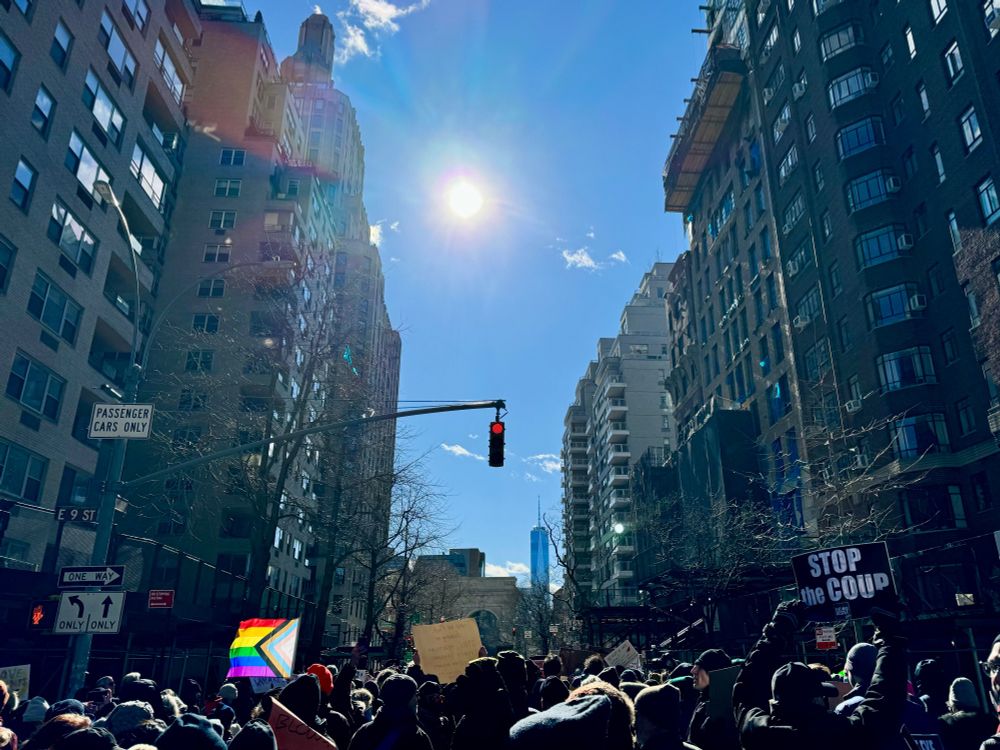 thousands of peaceful protesters (with an LGBT flag and a STOP THE COUP sign) march down Fifth Avenue, blocking traffic